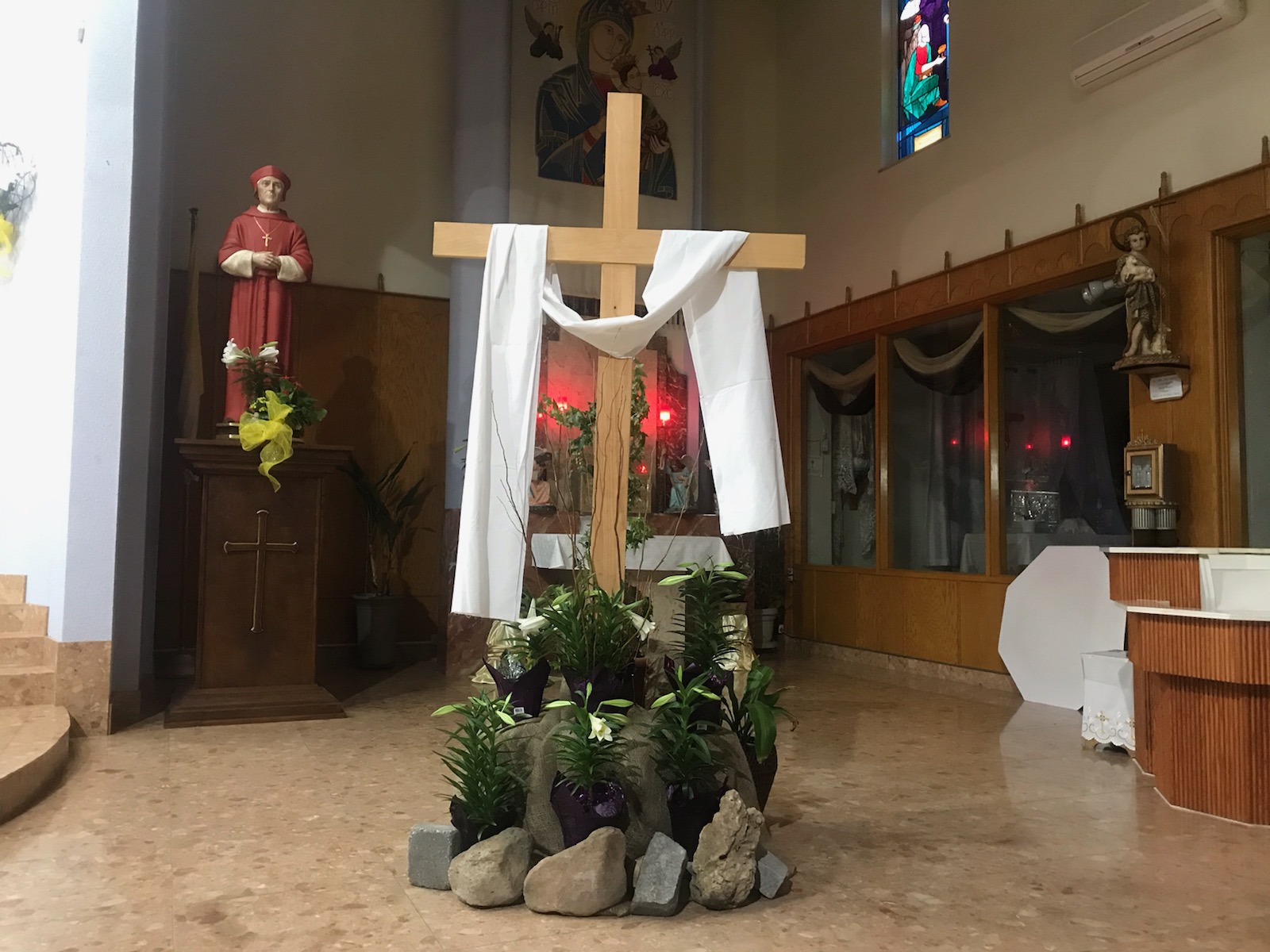 easter cross draped in white linen surrounded by rocks and lilies
