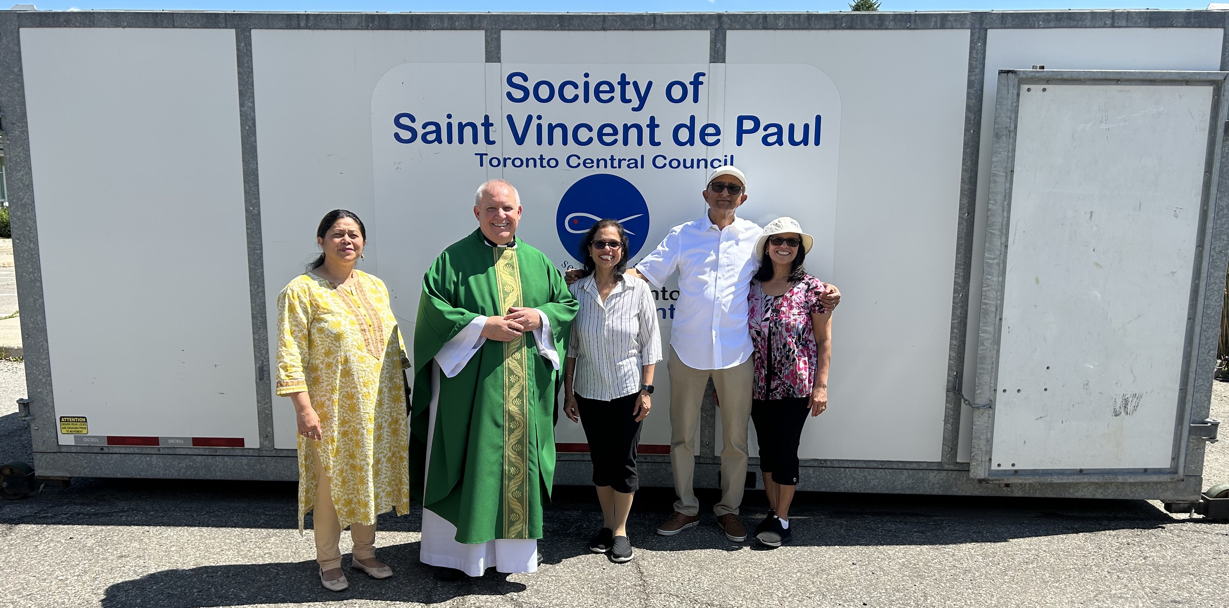 picture of fr. liborio, mignonne pinto, manuel  henriques and 2 other people in front of SSVP bundle up truck in July 2024
