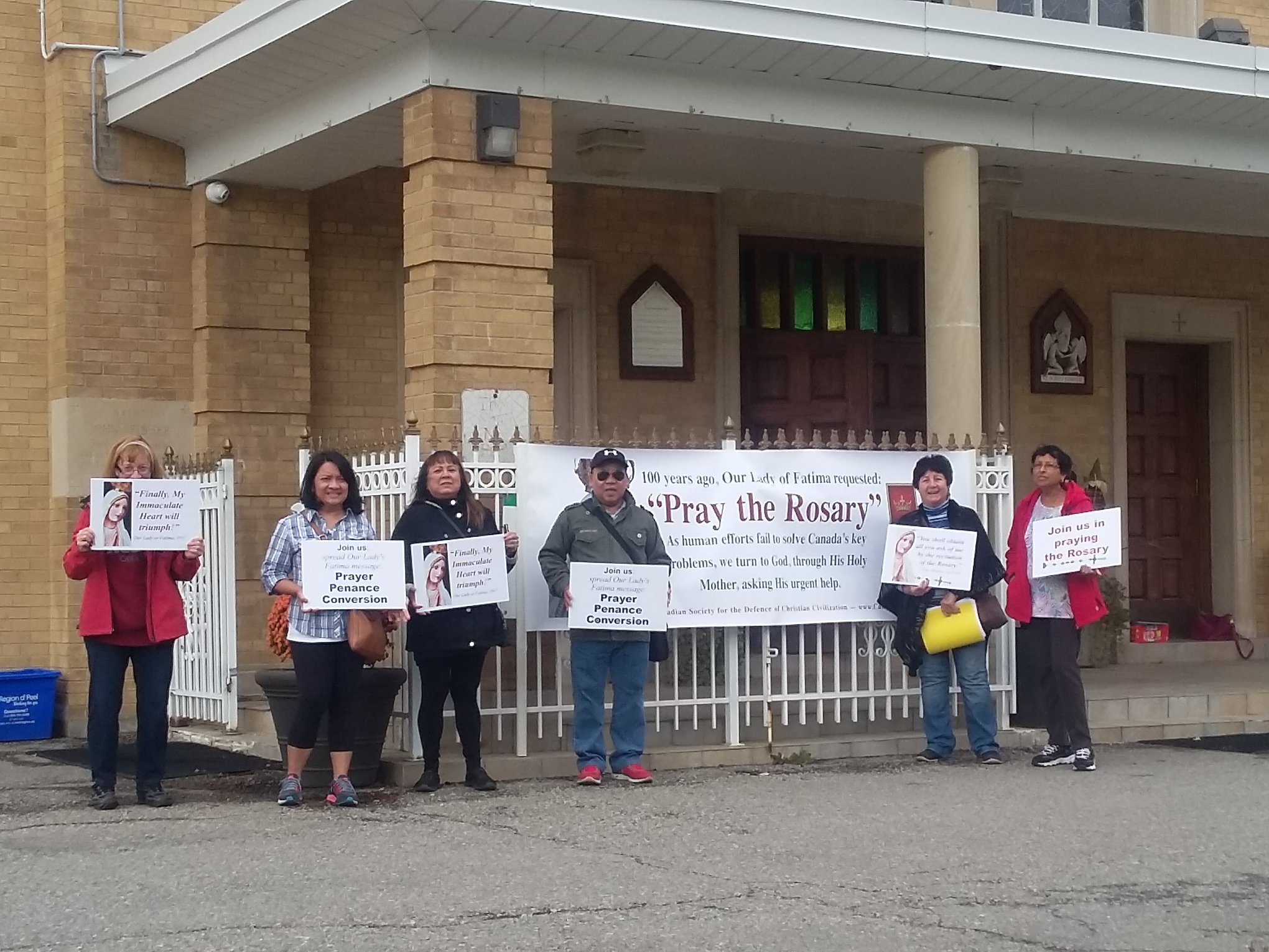 parishioners holding signs in front of church