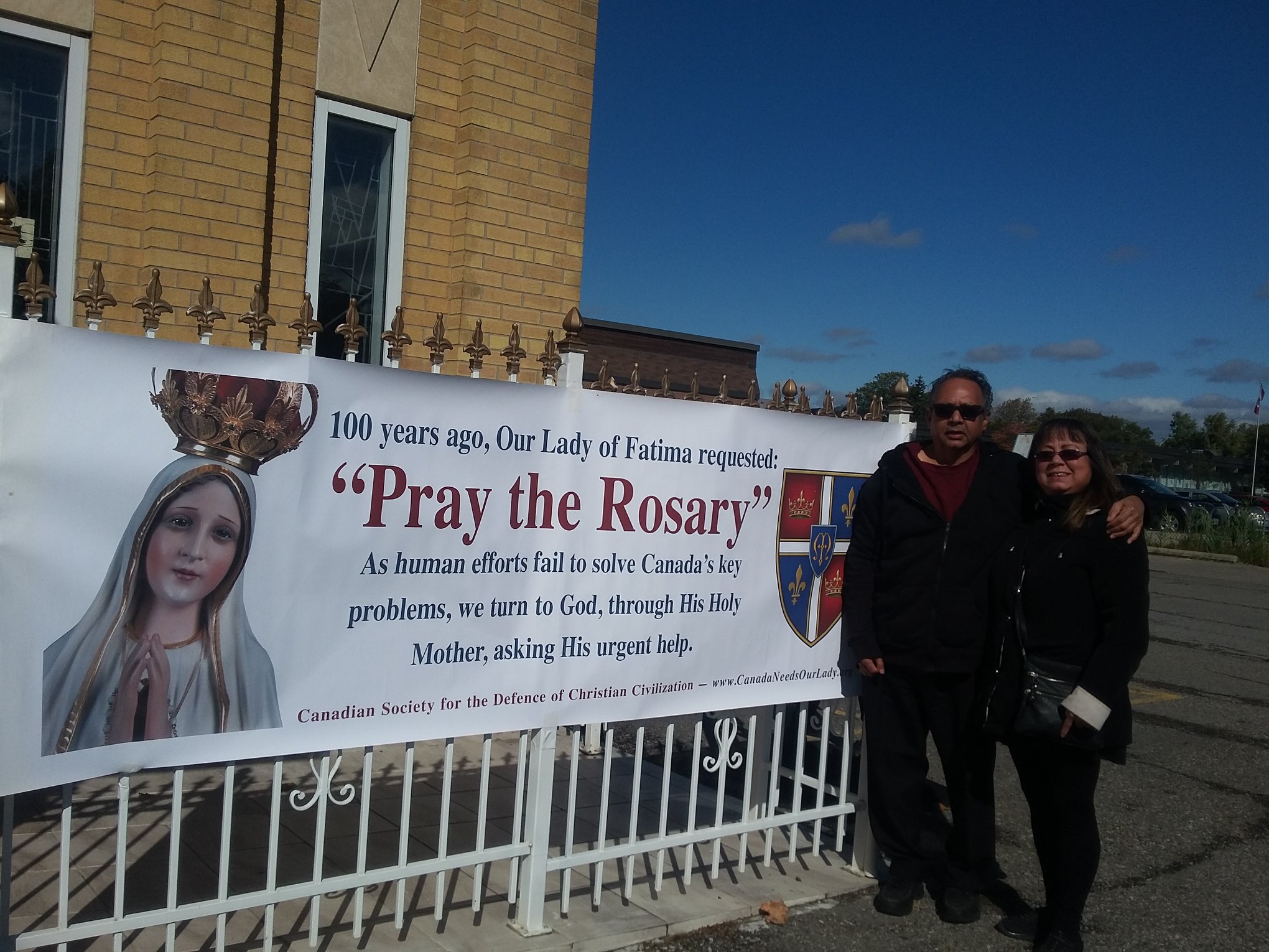 lorraine and james next to rosary rally sign